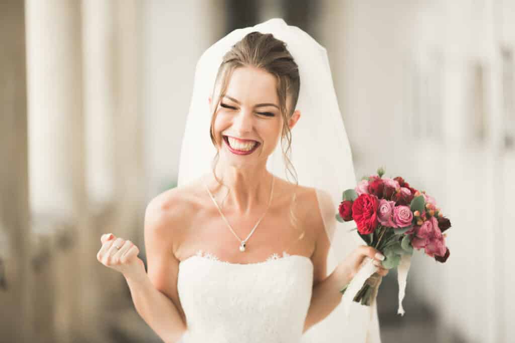 Happy young bride celebrating and smiling with bouquet.