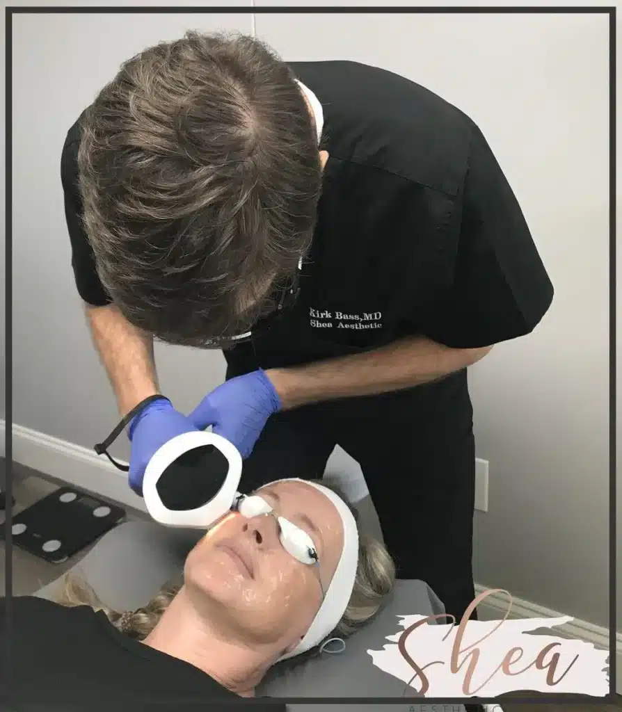 Providing photo facial treatment to young adult female upper cheek