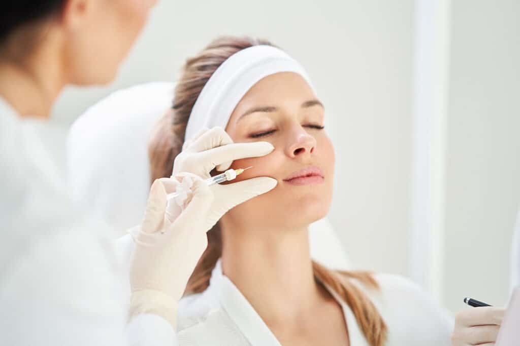 Young adult female receiving botox injection on upper cheek